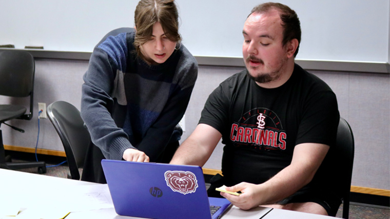 Two students working with laptop